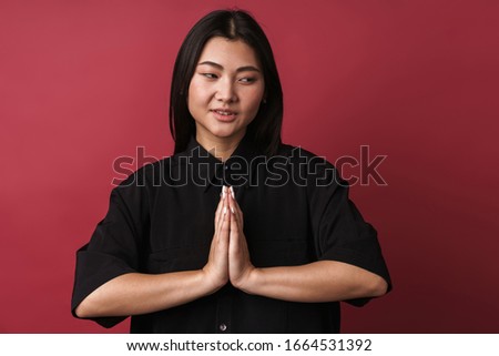 Photo of an asian optimistic relaxing young woman posing isolated over red wall background make meditate gesture.
