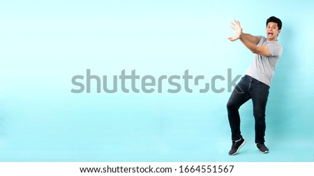 full body Portrait of handsome,Shock and surprise face of asian man Pointing finger on empty space isolated on blue background in studio With copy space.