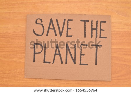 Handwritten Save the Planet cardboard sign on wood table background