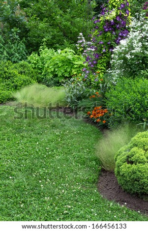 Beautifully landscaped blooming garden with green lawn.