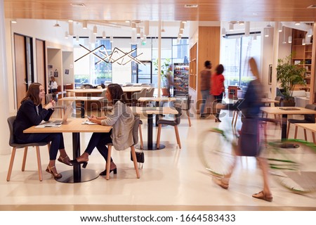 Interior Of Modern Open Plan Office With People Working And Commuters Arriving On Bikes Royalty-Free Stock Photo #1664583433