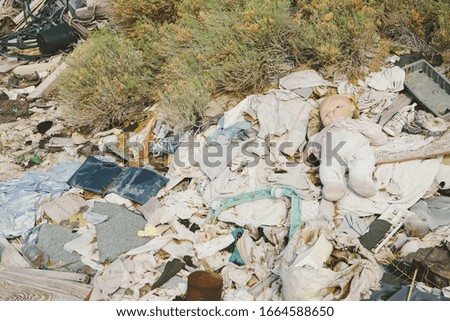 A heap of garbage and discarded items. Rubbish, paper and a children's doll.