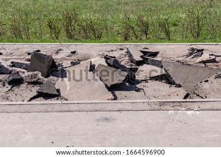 Massive asphalt damage with cracks at street/ A stack of pieces of broken asphalt/ Broken road, repair work at a construction site Royalty-Free Stock Photo #1664596900