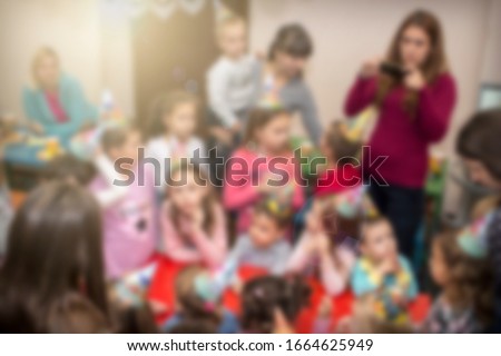 Blurred kids with their moms at birthday party in play room. Image for background use.