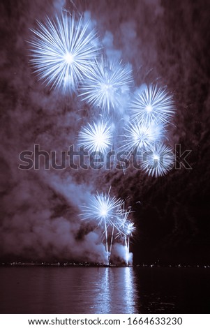 Luxury fireworks event sky water sea show with blue stars. Premium entertainment magic star firework at e.g. New Years Eve or Independence Day party celebration. Nice lake surface reflections