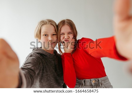 Funny brothers and sister take pictures of themselves. Girl in a red blouse,jeans and big earrings. Boy in a gray body shirt. Photo on a white background.
