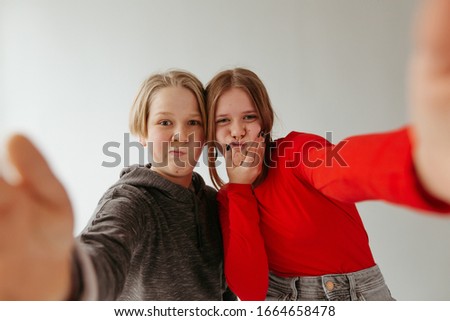 Funny brothers and sister take pictures of themselves. Girl in a red blouse,jeans and big earrings. Boy in a gray body shirt. Photo on a white background.