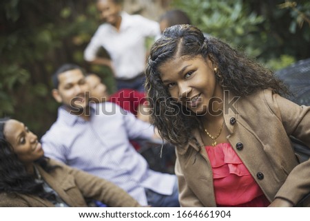 Scenes from urban life in New York City. A group of friends sitting together in a leafy square. Men and women. A teenage girl in the fore.