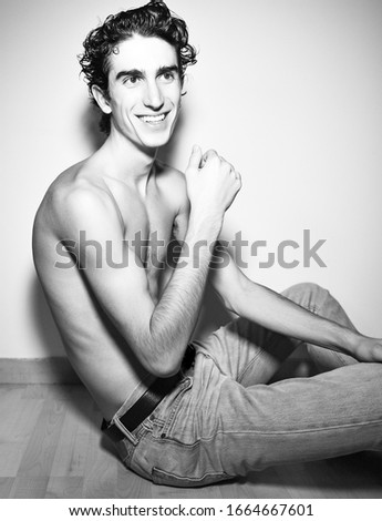 black and white.expressive mediterranean Italian dark haired handsome male model boy with angel face and fit sportive body posing for casual fashion shooting on wooden floor wearing jeans