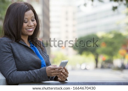 Summer in the city. Businesspeople outdoors, on the go. A woman in a grey suit with a bright blue shirt.