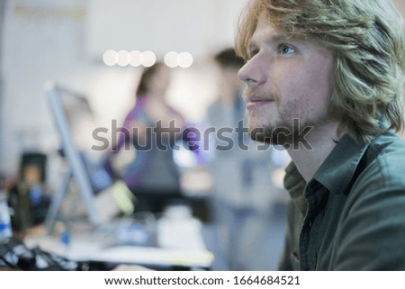 A man looking up from his task in a computer repair shop.