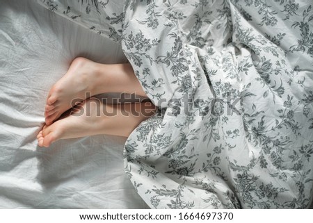legs stick out from under the covers. Morning sleepy photo.
