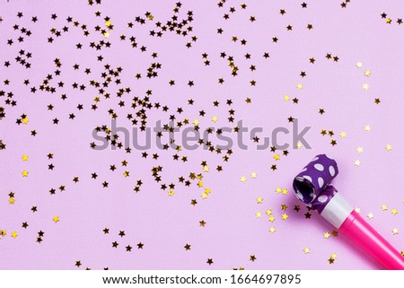 Birthday or party colorful happiness background with party noise whistles and confetti on pink background. Carnival air blowers flat lay, top view image.