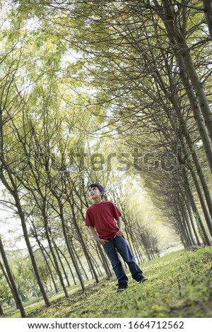A young boy in the woodland, looking around curiously. Royalty-Free Stock Photo #1664712562