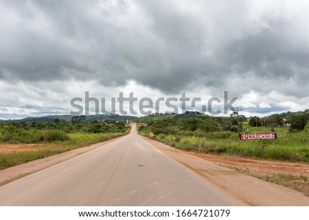 View of BR 163 road and sign of tire repair shop "borracharia" in Mato Grosso Amazon with farms in the background on a cloudy day. Dangerous road used to export soybeans from ports of Para, Brazil.