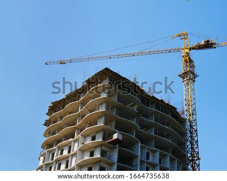 Construction site background. Hoisting crane and new multi-storey building. Industrial background.