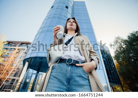 Young stylish woman drinking coffee to go in a city street