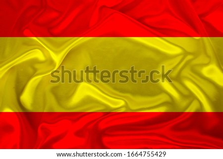 photo of the national flag of the state of Spain on a luxurious texture of satin, silk with waves, folds and highlights
