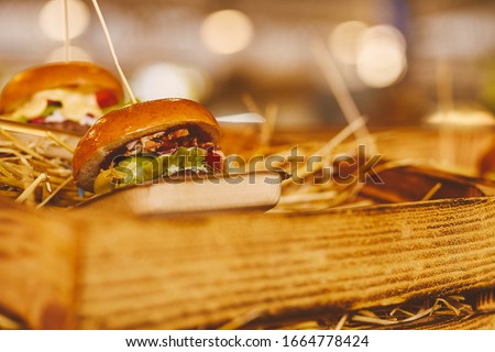 juicy hamburger with meat, herbs, tomato and cheese lies on the hay. street food. burger on a bokeh background. juicy hamburger for advertising. soft focus / close up photo. vintage photo processing.