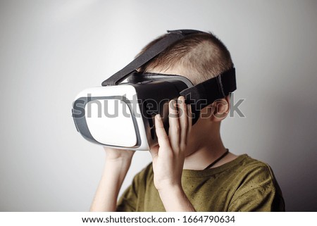 Boy playing mobile game app on device virtual reality glasses on white background. Boy action and using in virtual headset, VR box for use with smart phone. Contemporary technology concept, close up