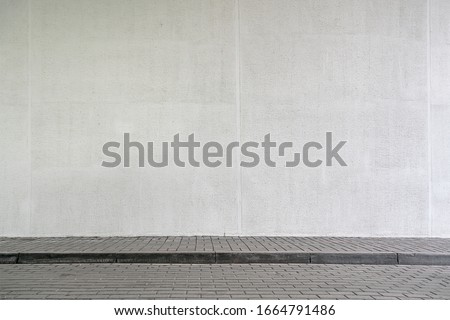 large modern building with high white wall near empty sidewalk covered with grey stone tiles on city street in spring Royalty-Free Stock Photo #1664791486