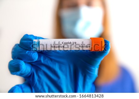 a doctor holds a coronavirus smear tube in her hand