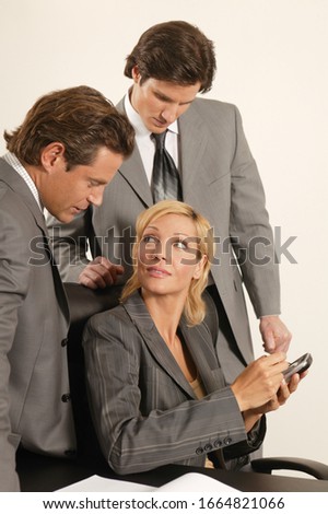 Three executives looking at an electronic notebook
