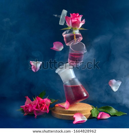 Several flasks are in the air. Levitation. Pink roses and flying petals. Blue background, smoke. Mystical picture.