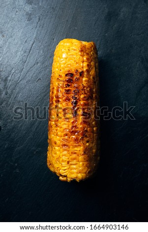 top view of roasted sweet corn on slate plate with black background. Healthy life concept.