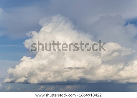Epic big white fluffy storm cumulus cloud in blue sky background, heaven