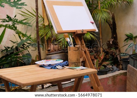 Wooden easel with blank painting paper as copy space for mock up in the gaden