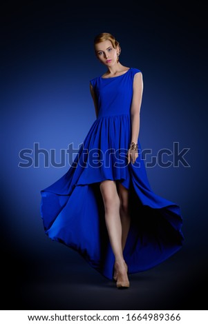 Fashion shot. Charming model in blue dress posing at studio. Hair, hairstyle.