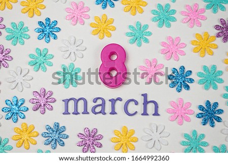 March made from purple letters, a purple 8 made of plastic and colorful little flowers on white background. International Women's Day decoration