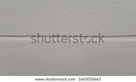 The grey surface that is smooth and has a light impact with scratched. White walls and shadows with warm afternoon sun. The wall is a white wall makes it look smooth and calming. Is a modern style.