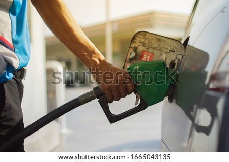 Refuel cars at the fuel pump. The driver hands, refuel and pump the car's gasoline with fuel at the petrol station. Car refueling at a gas station Gas station Royalty-Free Stock Photo #1665043135