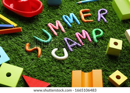 Composition with phrase SUMMER CAMP made of modelling clay on green grass