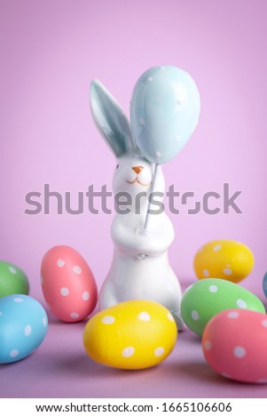 Easter bunny figure and dyed eggs on violet background