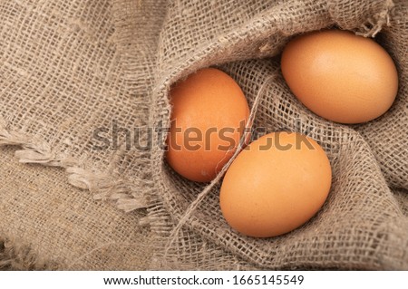 Chicken eggs on a background of rough homespun fabric. Rustic treat. Close up.