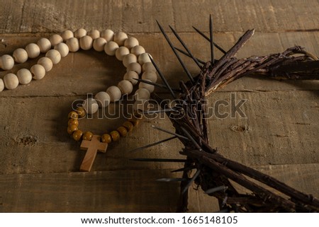 Concept of passion, crucifixion and resurrection. Iconic symbols related to Palm Sunday and Easter rest on a wooden table, crown of thorns and a rosary. Royalty-Free Stock Photo #1665148105