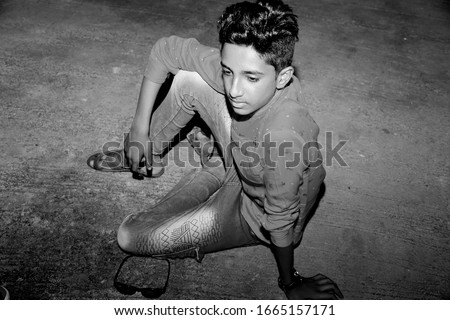 Indian rural child wearing red shirt is photographed at night. black and white picture.
