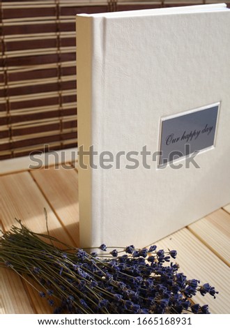 album photo book in a leatherette leather cover on a wooden background with a bouquet of lavender