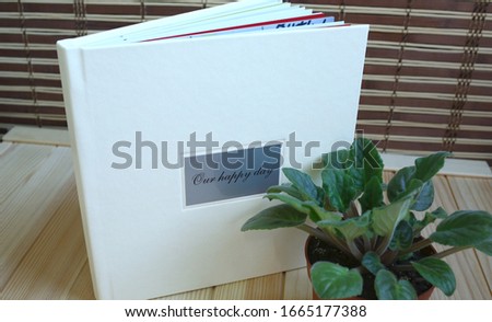 
album photo book in a leatherette leather cover on a wooden background with a 
decor flowers in a small pot