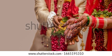 Very beautiful photo of a newly married Indian couple in ethnic attire offering flowers to God and taking blessings. Bride hands are decorated with henna design and colorful nuptial bangles. - Image Royalty-Free Stock Photo #1665195310