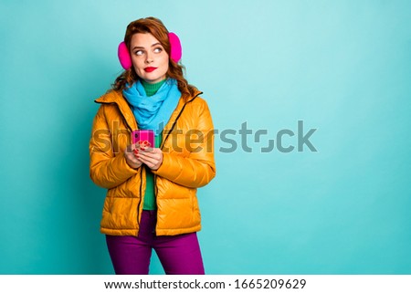 Photo of beautiful traveler lady hold telephone look side empty space minded have idea for new post wear casual yellow overcoat purple pants isolated teal color background