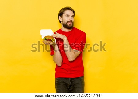 A man with a hamburger looks away Red T-shirt