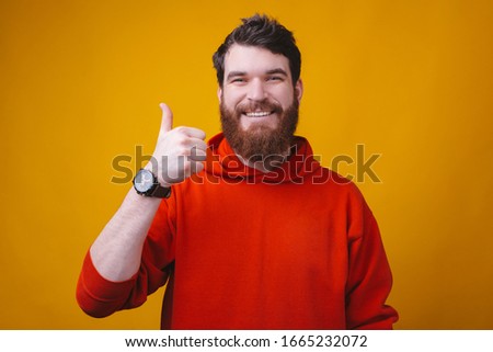 Photo of happy man with beard in red blouse showing thumbs up gesture