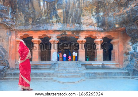 Young woman in traditional red clothes - Hindu sculptures in the cave - Elephanta Island, Mumbai - Maharashtra, India Royalty-Free Stock Photo #1665265924