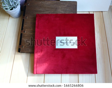 
album photo book with a metal insert and an inscription in a red villa cover with a decor next to flowers