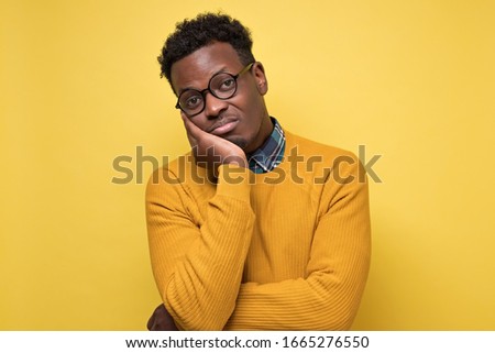Bored African American college student is tired and bored with exaams and studies. Studio shot