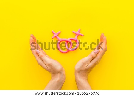 LGBT concept. Female Venus symbols in hands on yellow background top-down